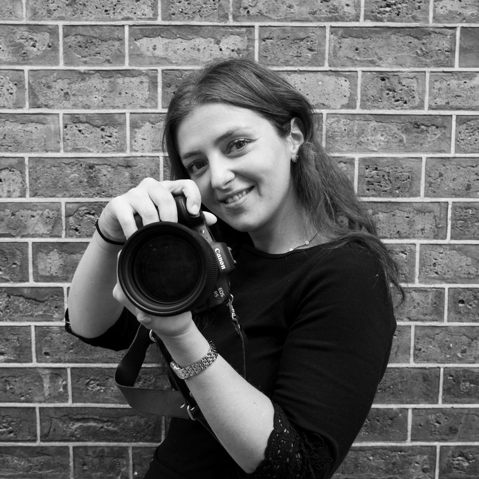 Tuğla duvar önünde fotoğraf makinesiyle genç kadın